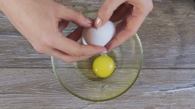 Female Hand Breaks Egg In A Bowl