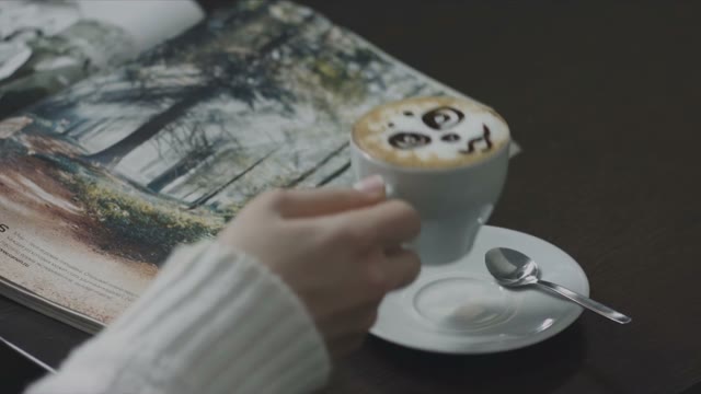 Girl Drinks Coffee With Foam And Leafing Through A Magazine