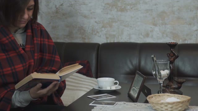 Girl In Plaid Sitting And Reading A Book And Drinking Tea In A Cafe
