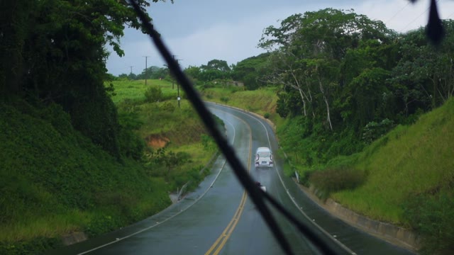 Wet Road In The Tropics With Passing Motorcycles