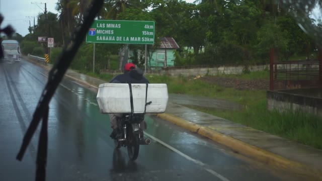 A Local Resident Rides A Bicycle With A Big Box In The Rain