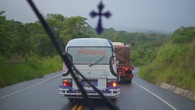 Passing Cars On The Road Among The Green Trees On A Cloudy Day