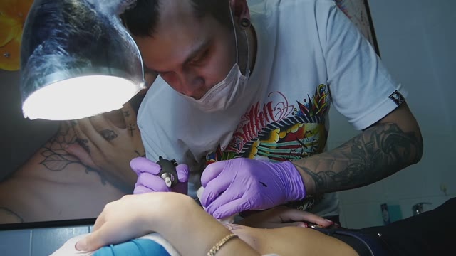 Tattoo Master Makes The Tattoo On A Woman's Body