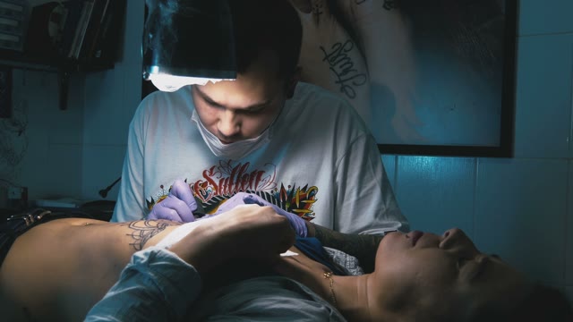 Tattoo Master Makes The Tattoo On A Woman's Body