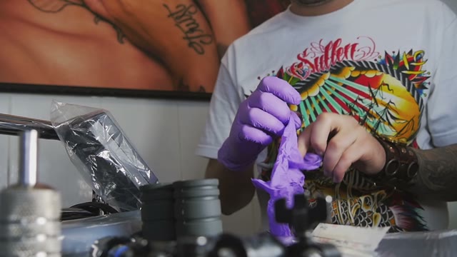 Man With Tattoos Puts On Gloves Close-up