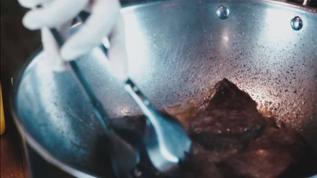 The Chef In White Gloves Flips The Meat In A Skillet