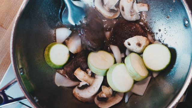 The Chef In White Gloves Preparing Meat With Mushrooms And Zucchini