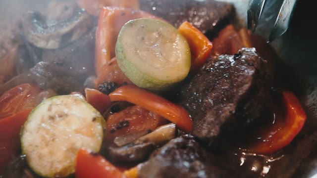 Steamed Vegetables With Meat In An Iron Skillet Mix With Tongs