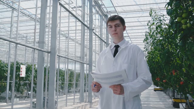 A Scientist With A Table In The Hands Of The Middle Of The Greenhouse With