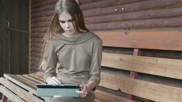 Girl Sits On A Bench With A Tablet