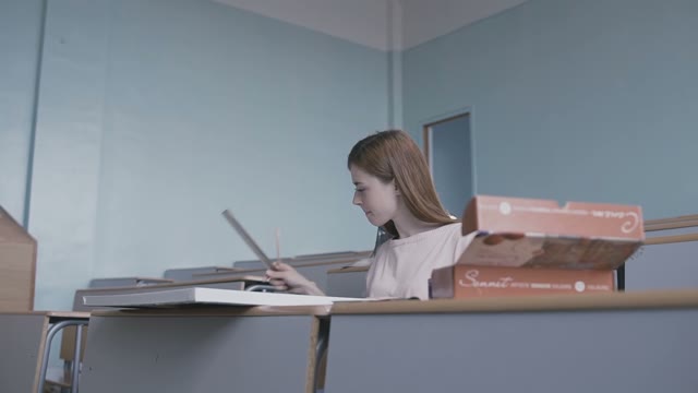 Red-haired Girl Sitting In The Classroom And Working With A Ruler And Drawing