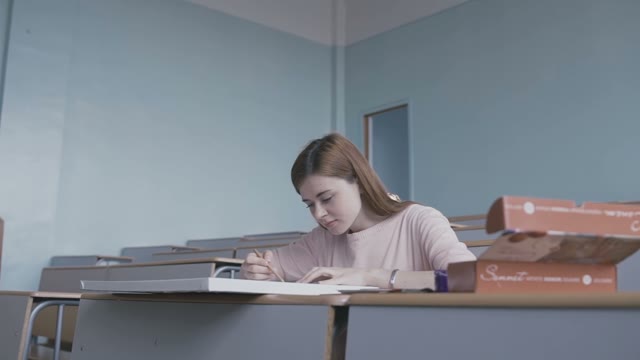 Red-haired Girl Sitting At The Desk And Is Working On A Picture