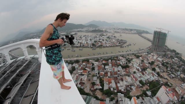 Man Standing On The Edge Of A Tall Building And Shoots