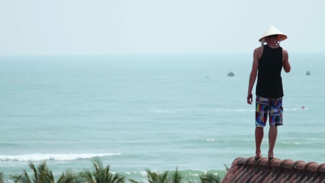 Man Standing On A Rooftop In The Background Of The Sea