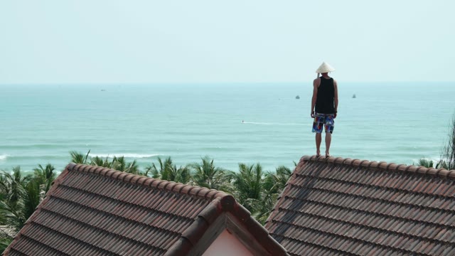 Man Standing On A Rooftop In The Background Of The Sea