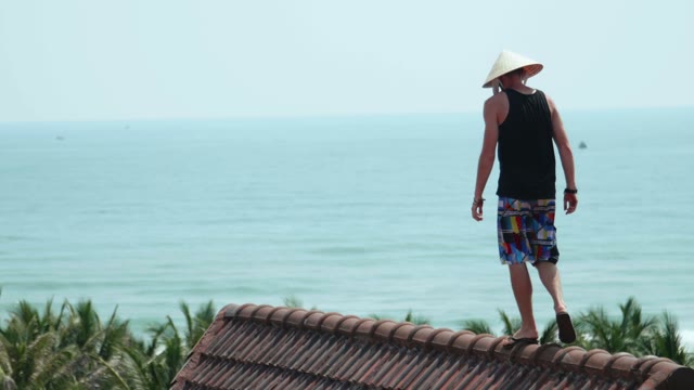 Man On A Rooftop In The Background Of The Sea