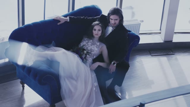 Bride Lying On The Big Blue Sofa And Caresses Her Fiance