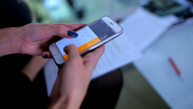 Female Hands Consider The Numbers On A Calculator In The Phone