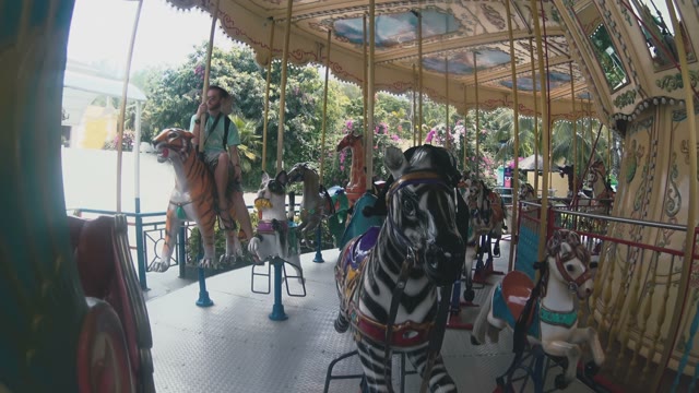 Girl And Guy Rides On The Carousel