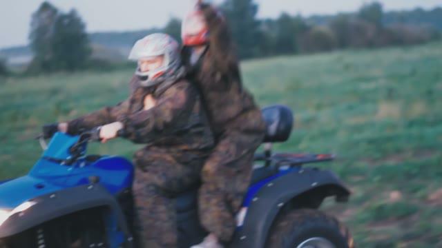 Boy And Girl On ATV Riding And Having Fun Waving Arms