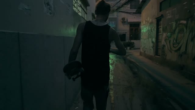 Man Walks With A Skateboard In Hands At Night