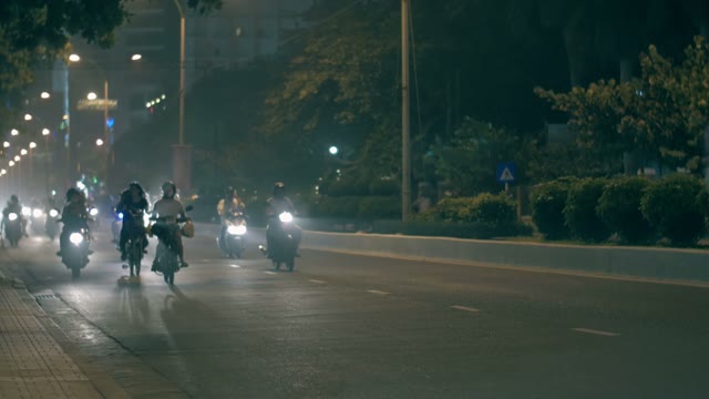 People Riding On Mopeds At Night