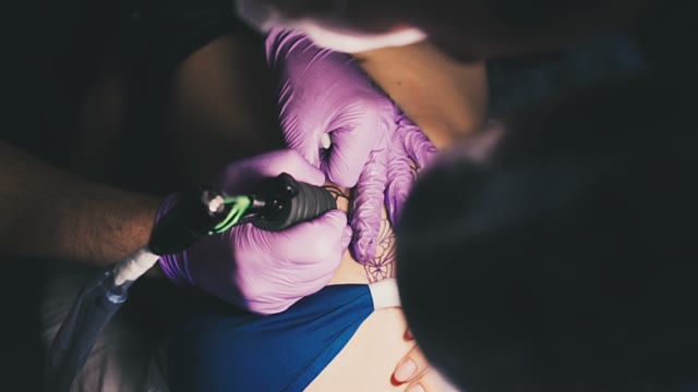 Tattoo Artist Draws A Tattoo On The Body Of A Young Beautiful Attractive Girl