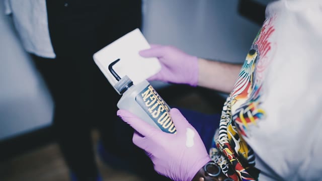 Tattoo Master Covers A Cloth With A Disinfectant