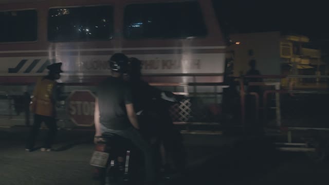 People On Mopeds Move Across The Railway Crossing