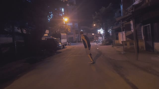 Man Riding A Skateboard On The Road At Night