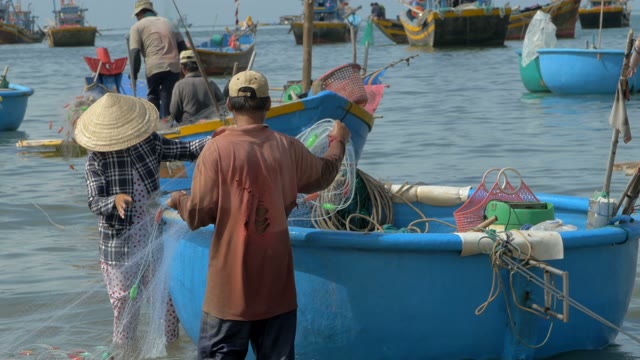 A Man And A Woman Placed A Fishing Net In A Boat