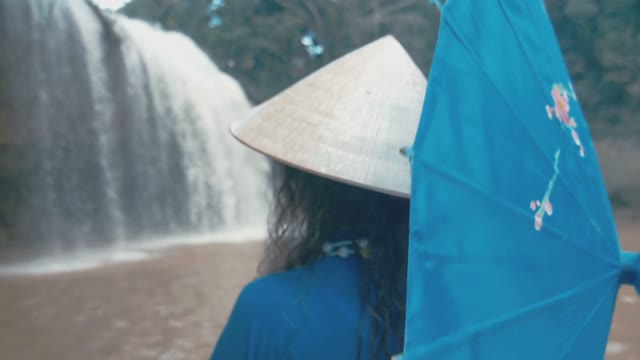 Girl With Umbrella On The Background Of A Small Waterfall Close-up