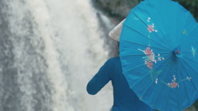 Girl With Umbrella On The Background Of A Small Waterfall Close-up
