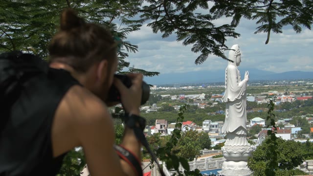 Photographer Shoot At The Camera A Large Statue Of A Tall White Buddha
