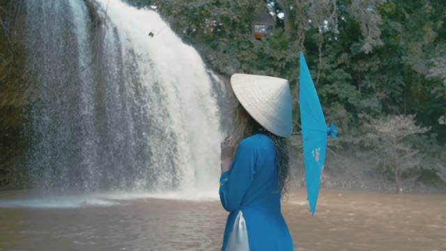 Girl With Umbrella On The Background Of A Waterfall