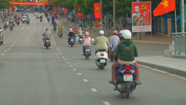 Motorcyclists Riding On The Road Decorated With Red Flags