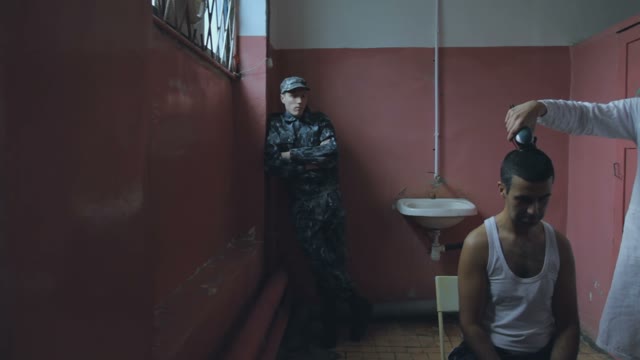 The Prison Warden Watches Over The Process Of Criminal Haircut