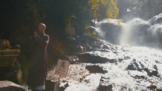 Monk Stands Near The Waterfall