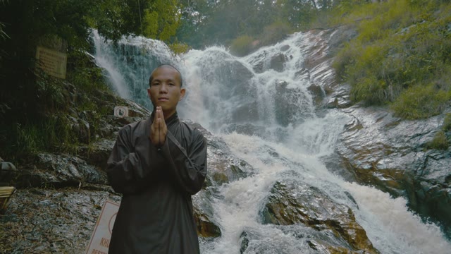 Monk Stands Near The Waterfall