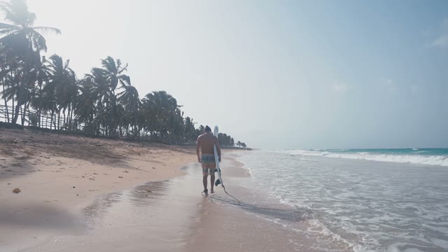 Young Beautiful Dark-haired Surfer Walking Along A Tropical Beach