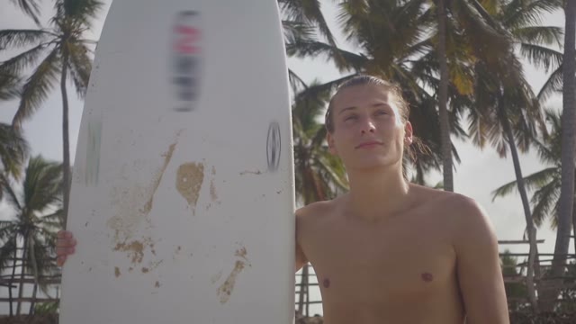 Nice Young Surfer With A Good Physique Stands On The Beach