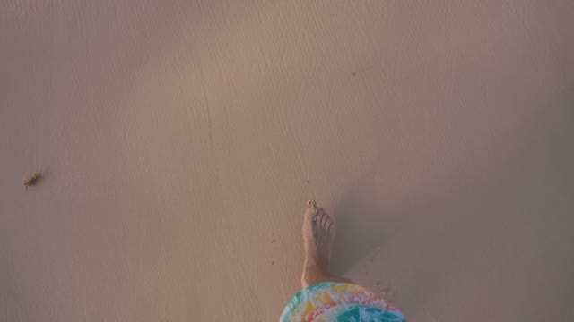 A Man Walks Barefoot Along The Beach
