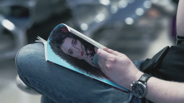 The Man With The Clock On The Hand Leafing Through A Glossy Magazine