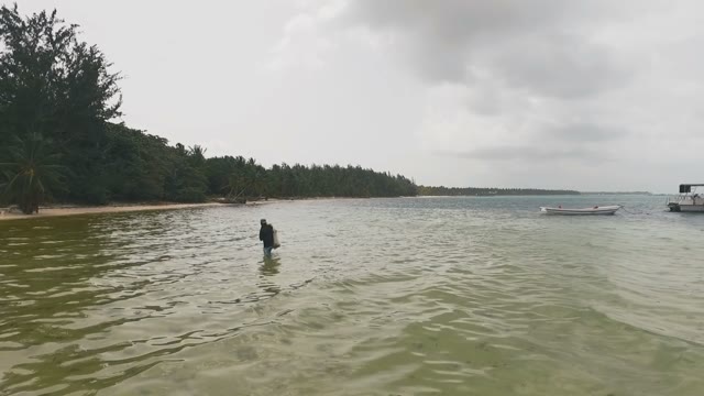 A Man Comes Out Of The Water With A Net Full Of Fish