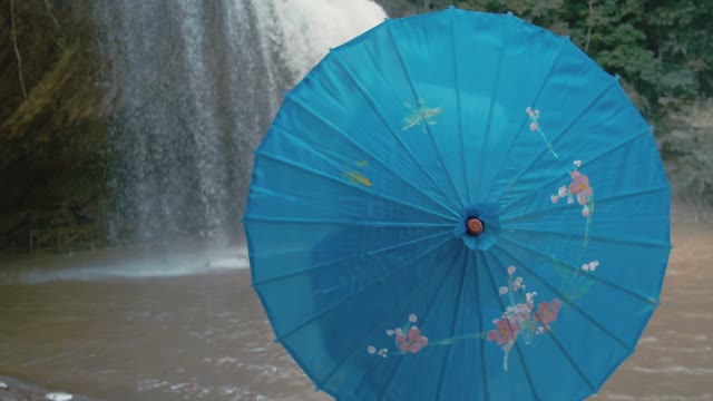 Girl With Umbrella On The Background Of A Waterfall Close-up