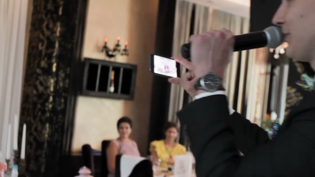 Man Speaks Into A Microphone And Takes Pictures On A Smartphone