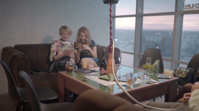 Two Girlfriends Are Relaxing In A Restaurant