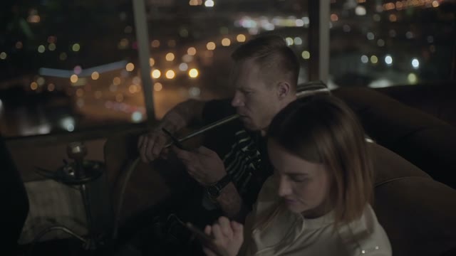 Man Smoking A Hookah With Smartphone Close-up