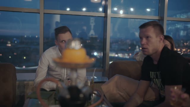 Company Of Friends Communicate And Smoke A Hookah