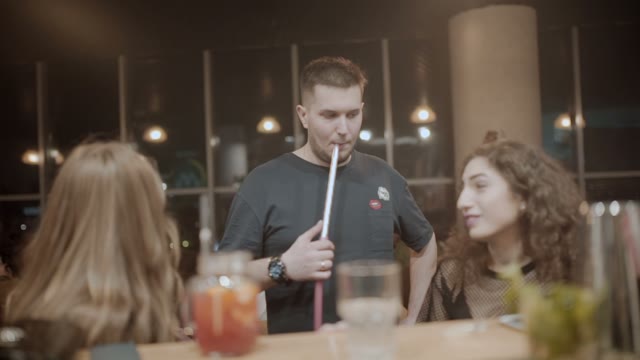 Man Smokes A Hookah In The Presence Of Girls